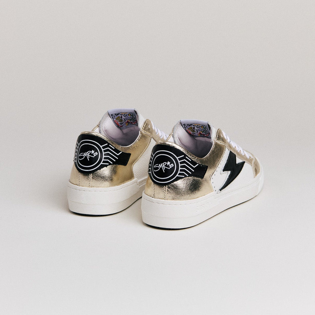 Zoom sur le logo éclair noir et cuir métallisé or Semerdjian